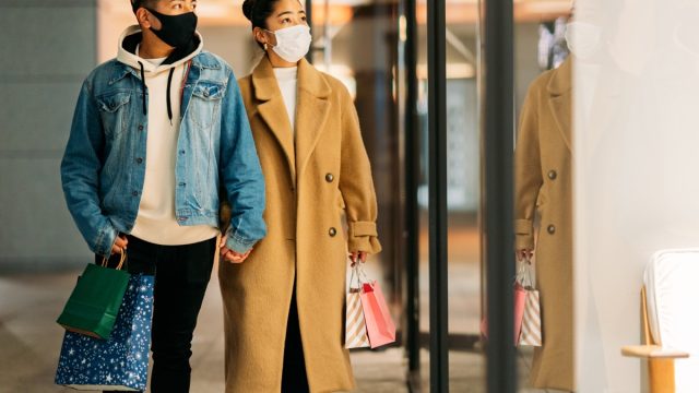couple is shopping in the city while wearing protective face masks for illness prevention in winter.