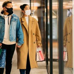 couple is shopping in the city while wearing protective face masks for illness prevention in winter.