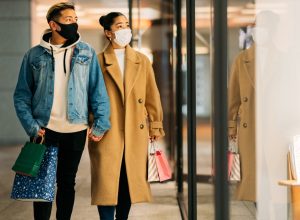 couple is shopping in the city while wearing protective face masks for illness prevention in winter.