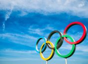 A statue of the Olympic rings set against a blue sky