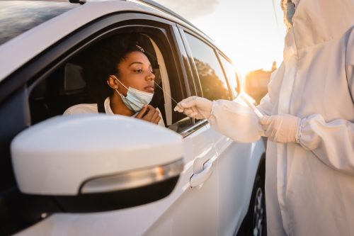 A woman sitting in her car getting her nose swabbed as part of a COVID-19 test