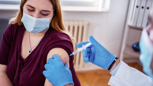 A young woman receiving a COVID-19 vaccine or booster shot from a healthcare worker or doctor