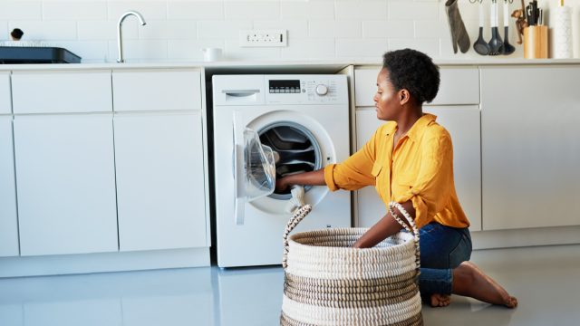 A woman loading items into a washing machine