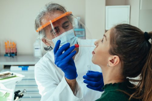 A young woman getting a nasal swab for a COVID test from a healthcare worker