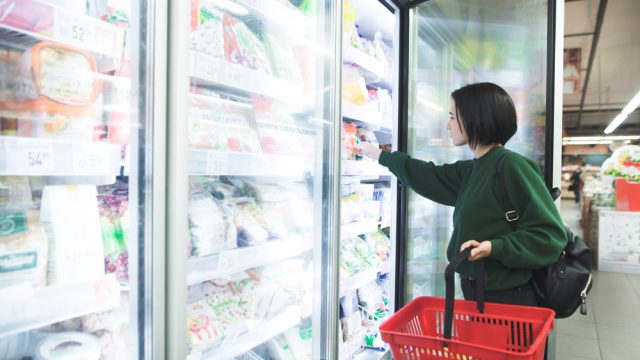 A woman shopping in the freezer section of a grocery store