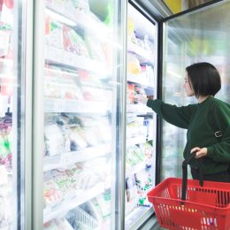 A woman shopping in the freezer section of a grocery store