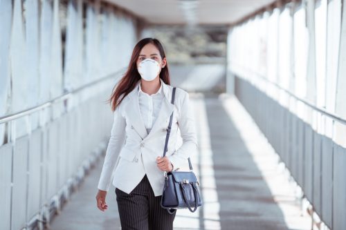 ผู้หญิงกำลังจะไปทำงาน เธอสวมหน้ากาก N95 ป้องกันฝุ่น PM2.5 และหมอกควัน