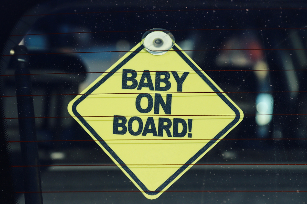A baby on board sign hanging in the back of a car