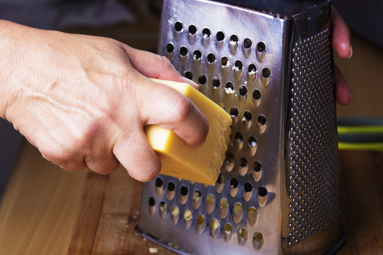 Close up of a piece of cheese being used on a cheese grater