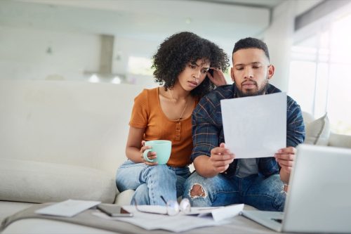 Кадър на млада двойка, изглеждаща стресирана, докато разглежда финансите си у дома