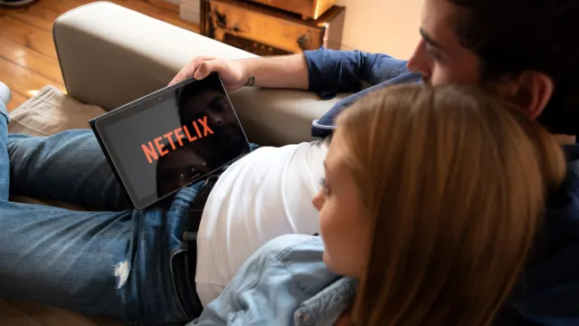 A couple watching Netflix on their tablet while sitting on a couch