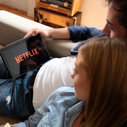 A couple watching Netflix on their tablet while sitting on a couch