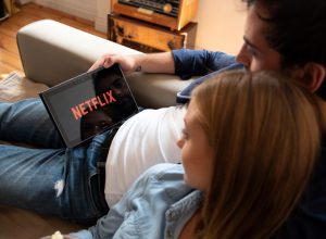 A couple watching Netflix on their tablet while sitting on a couch