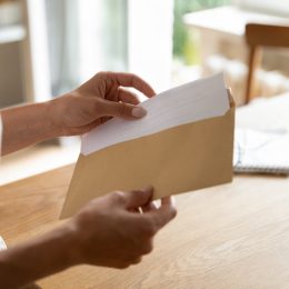 Postal correspondence. Close up view of young woman open paper letter message document prepare to read news view information. Female hands put written note in envelop before send it by mail to friend