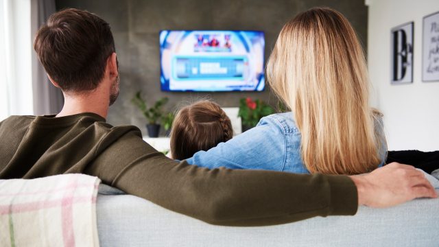 A family sitting on a couch while watching a streaming TV service