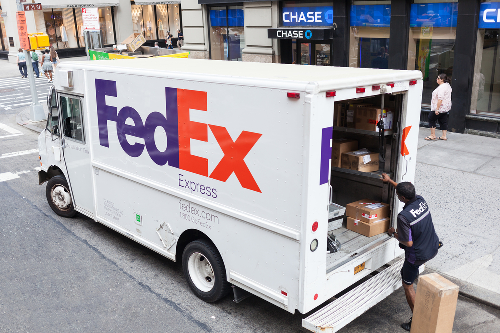 A FedEx truck being loaded by a delivery worker