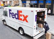 A FedEx truck being loaded by a delivery worker