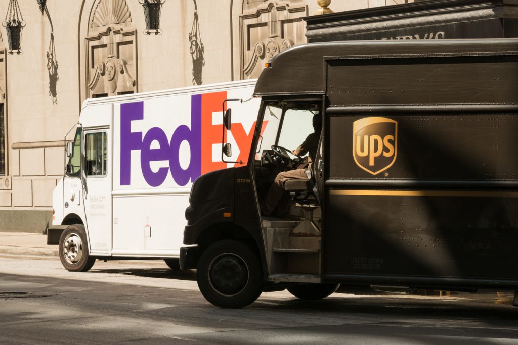 A UPS and FedEx delivery truck next to each other on the street