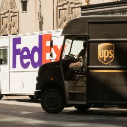 A UPS and FedEx delivery truck next to each other on the street