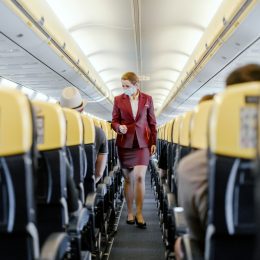 A flight attendant walking down the aisle of a plane checking on passengers