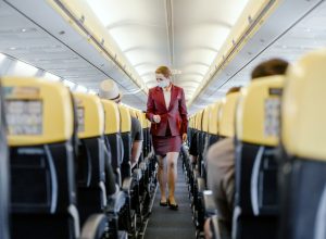 A flight attendant walking down the aisle of a plane checking on passengers