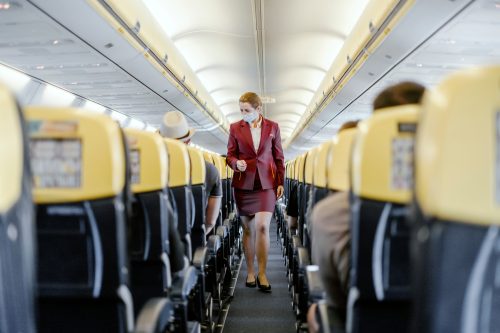 A flight attendant walking down the aisle of a plane checking on passengers
