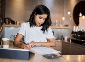 Female cafe owner signing papers calculating business expenses