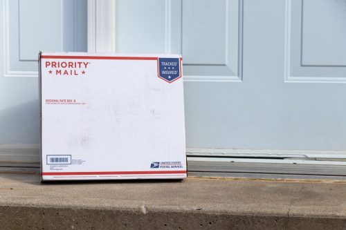 Пакет с услуга за пратки на САЩ (USPS), доставен до входната врата.