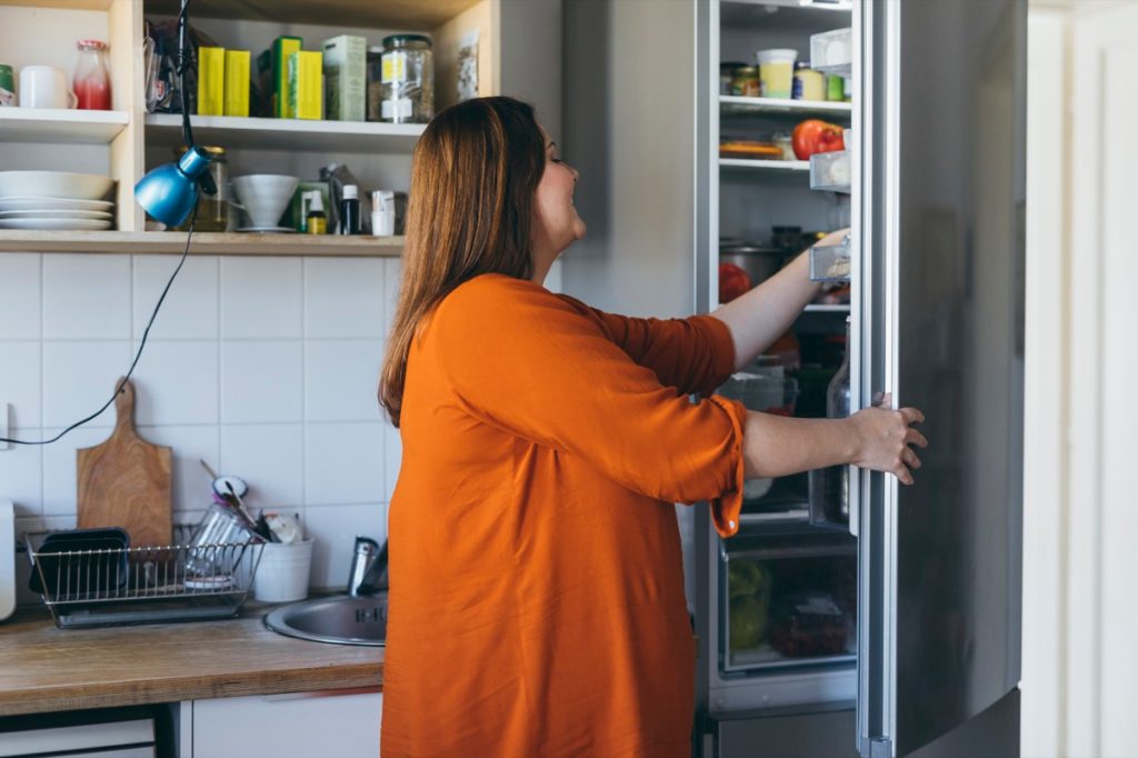 žena bere něco z lednice, aby udělala snídani v kuchyni