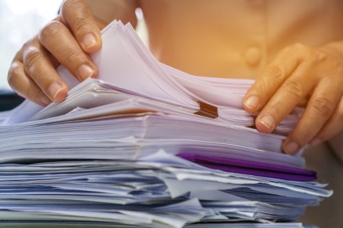 Businesswoman hands working in Stacks of paper files for searching information on work desk office, business report papers,piles of unfinished documents achieves with clips indoor,Business concept