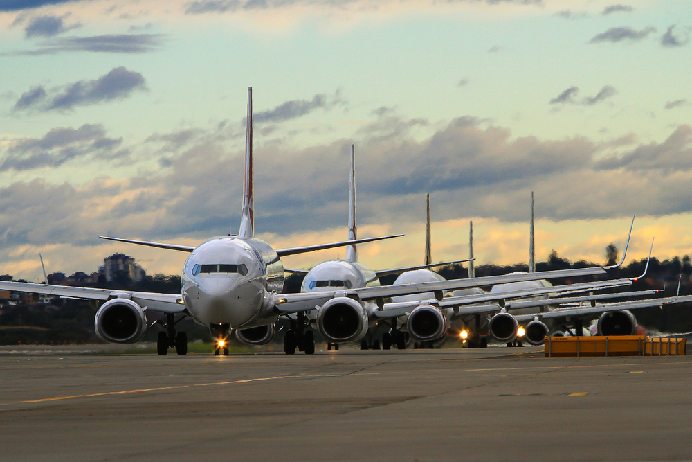 A row of planes taxiing on a runway for takeoff