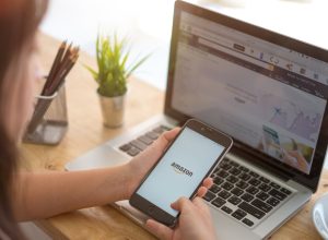 A woman shopping on Amazon using a laptop and phone