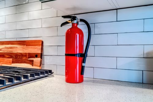 close up of fire extinguisher next to stove in kitchen