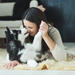 woman getting her nose kissed by her dog while holding its paw