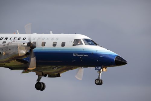 An Embraer EMB-120ER Brasilia operated by SkyWest Airlines for United Express is guided in by the pilots for a sunset landing at Portland International Airport.