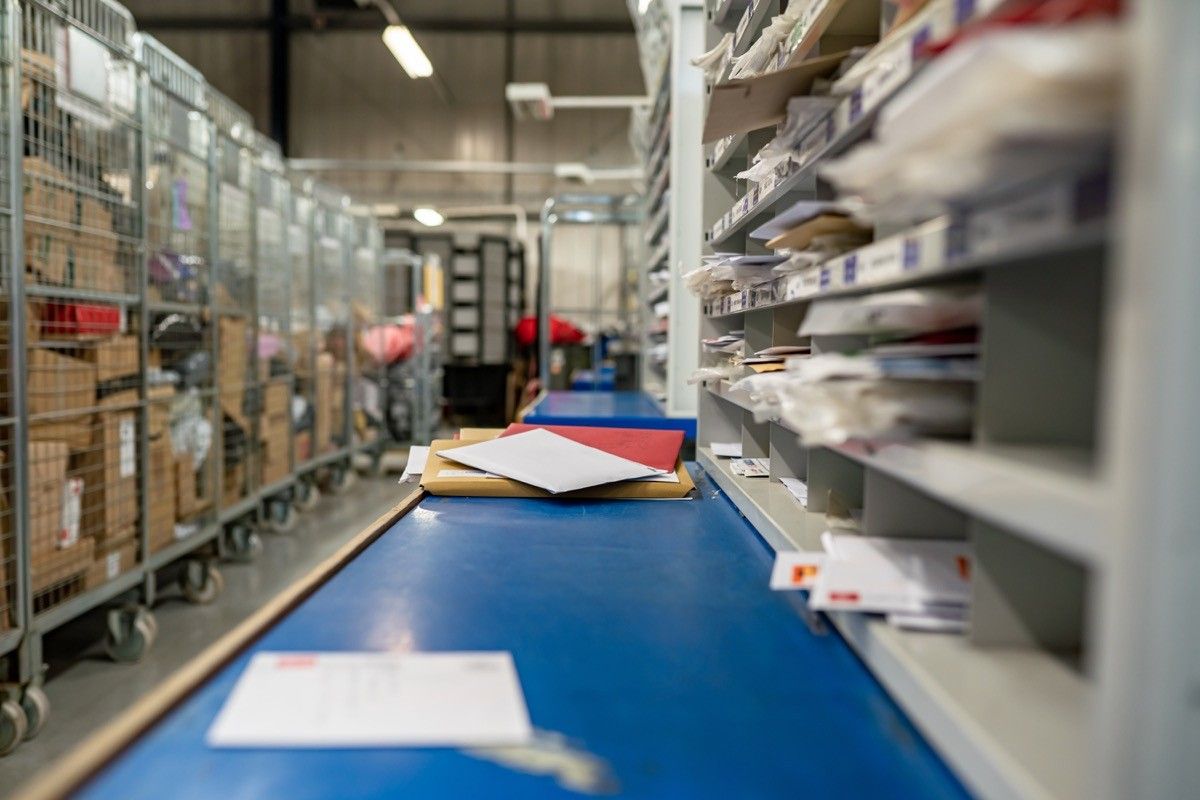 Postal service, post office inside. Letters on a sorting frame, table and shelves in a mail delivery sorting centre.