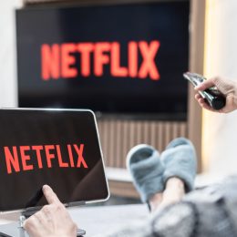 A person sitting on a couch watching Netflix on their TV and tablet