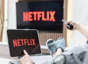 A person sitting on a couch watching Netflix on their TV and tablet
