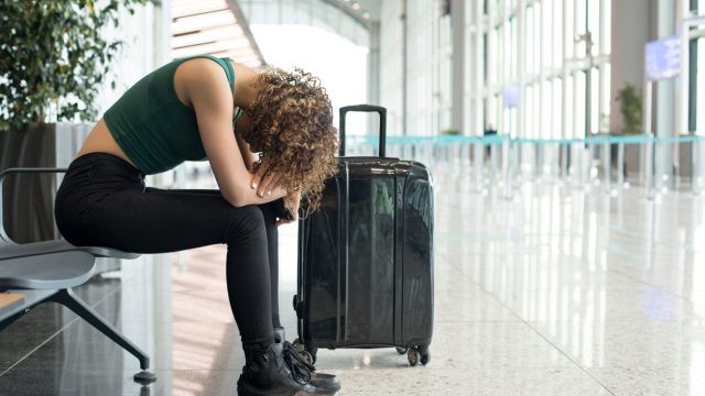 A woman waiting in the airport with her head down after a flight was canceled