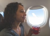 A woman drinking a beverage or cocktail on a flight