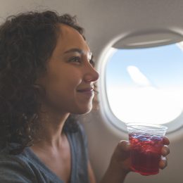 A woman drinking a beverage or cocktail on a flight