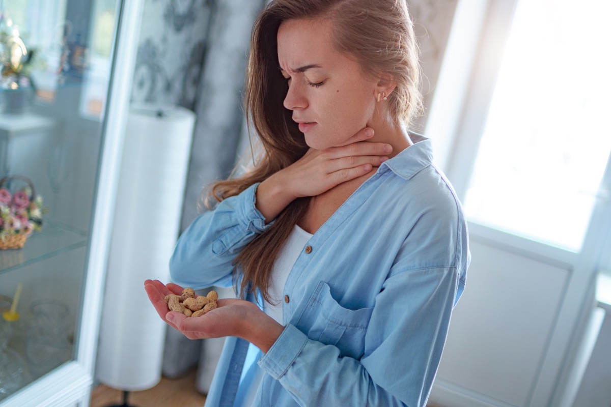 Woman choking on food, holding peanuts
