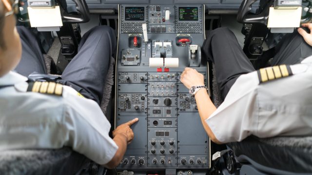 A pilot and copilot sitting in the cockpit of a commercial airliner
