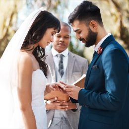 Cropped shot of an affectionate young groom slipping a ring on to his bride's finger while standing at the altar on their wedding day