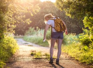 Woman applying insect repellent against mosquito and tick on her leg during hike in nature. Skin protection against insect bite