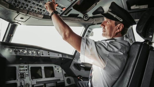 A commercial airline pilot pressing controls in the cockpit