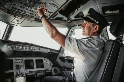 A commercial airline pilot pressing controls in the cockpit