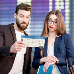 A couple looking at their flight boarding pass with a concerned look on their faces
