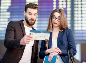 A couple looking at their flight boarding pass with a concerned look on their faces