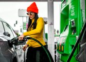 A fancy woman pouring some fuel in her car.
